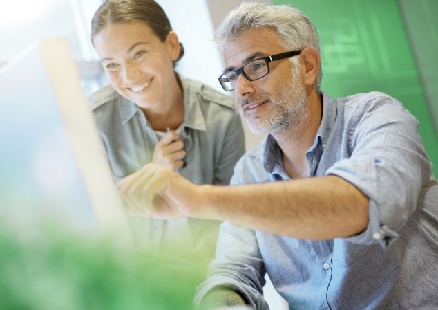 Ein Mann und eine Frau schauen sich Informationen auf einem Notebook an.