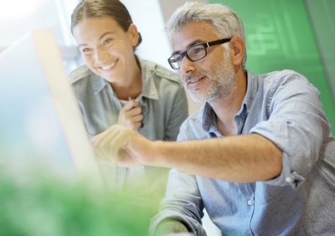 Ein Mann und eine Frau schauen sich Informationen auf einem Notebook an.